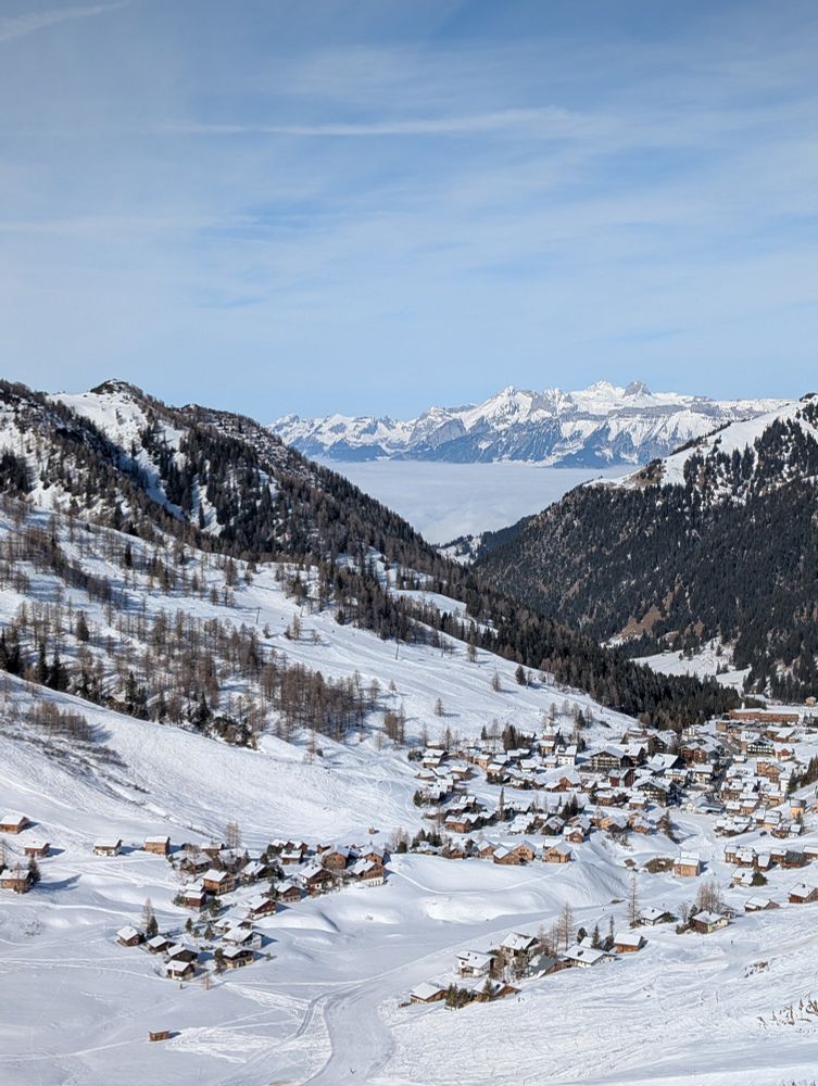 Blick durch das Tal auf Malbun mit Nebelmeer im Hintergrund.