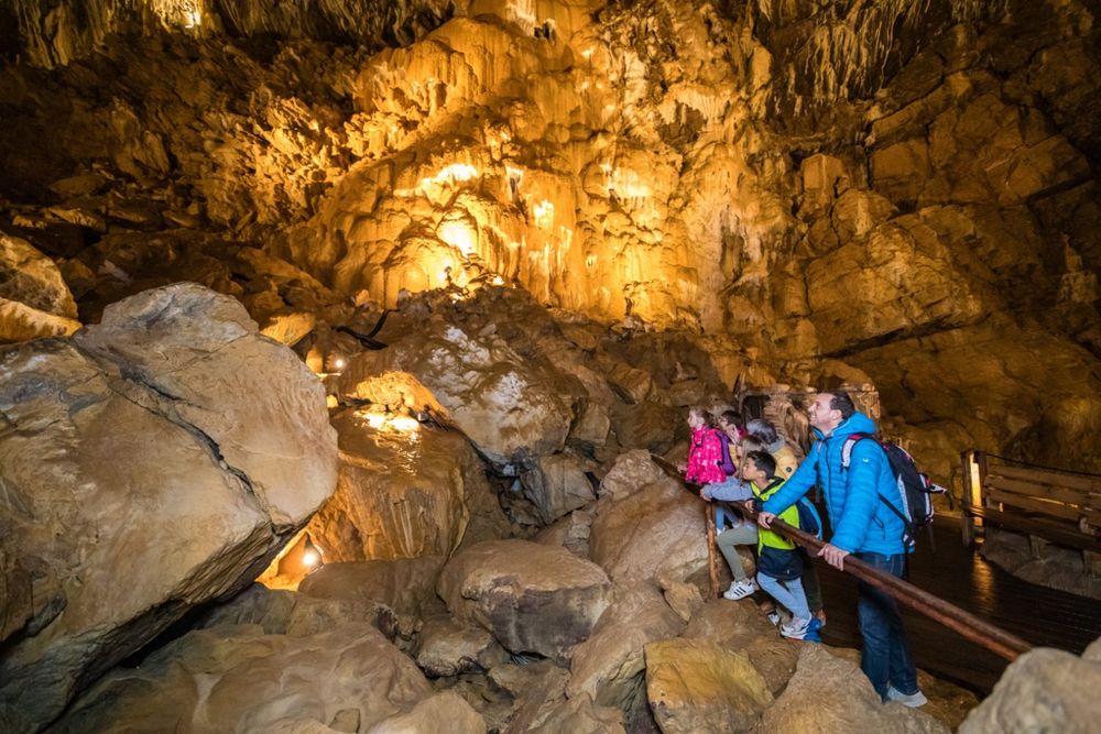 Eine Familie betrachtet eine beleuchtete Tropfsteinhöhle. (Bild: YlBR Vallorbe Grottes / www.vincentbourrut.ch)