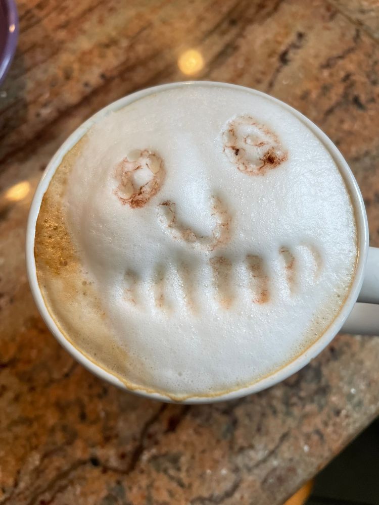 Top-down image of frothed milk foam worked into a skull shape in coffee mug