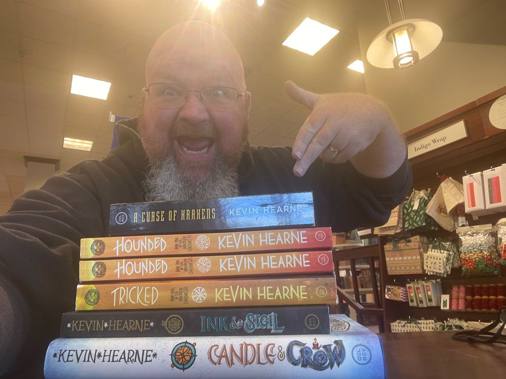 My goofy self pointing at six books I signed in Chapters: Hounded, Tricked, Ink & Sigil, Candle & Crow, and A Curse of Krakens.