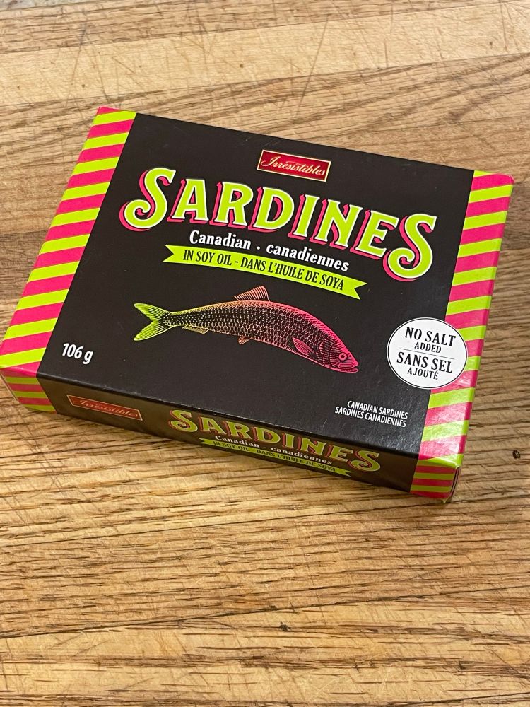 A package of sardines in soy oil laid out on a wooden cutting board.