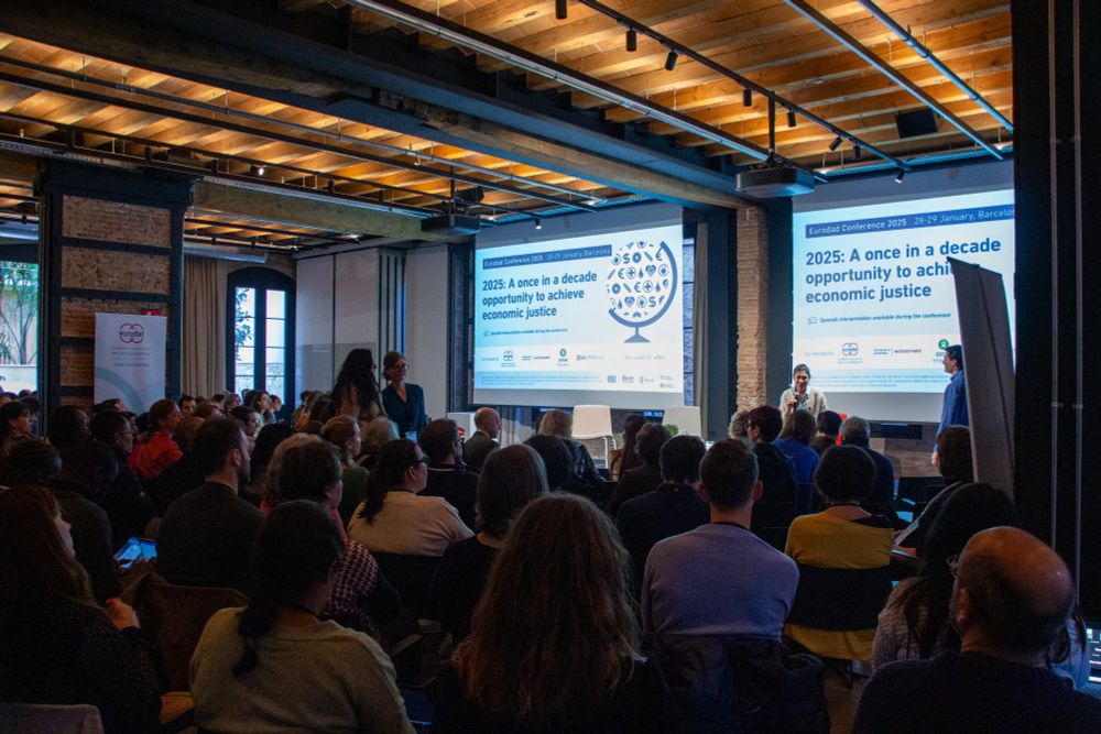 A plenary session at the Eurodad Conference. Participants are looking towards the front of the room where the screen reads "2025: A once in a decade opportunity to achieve economic justice"