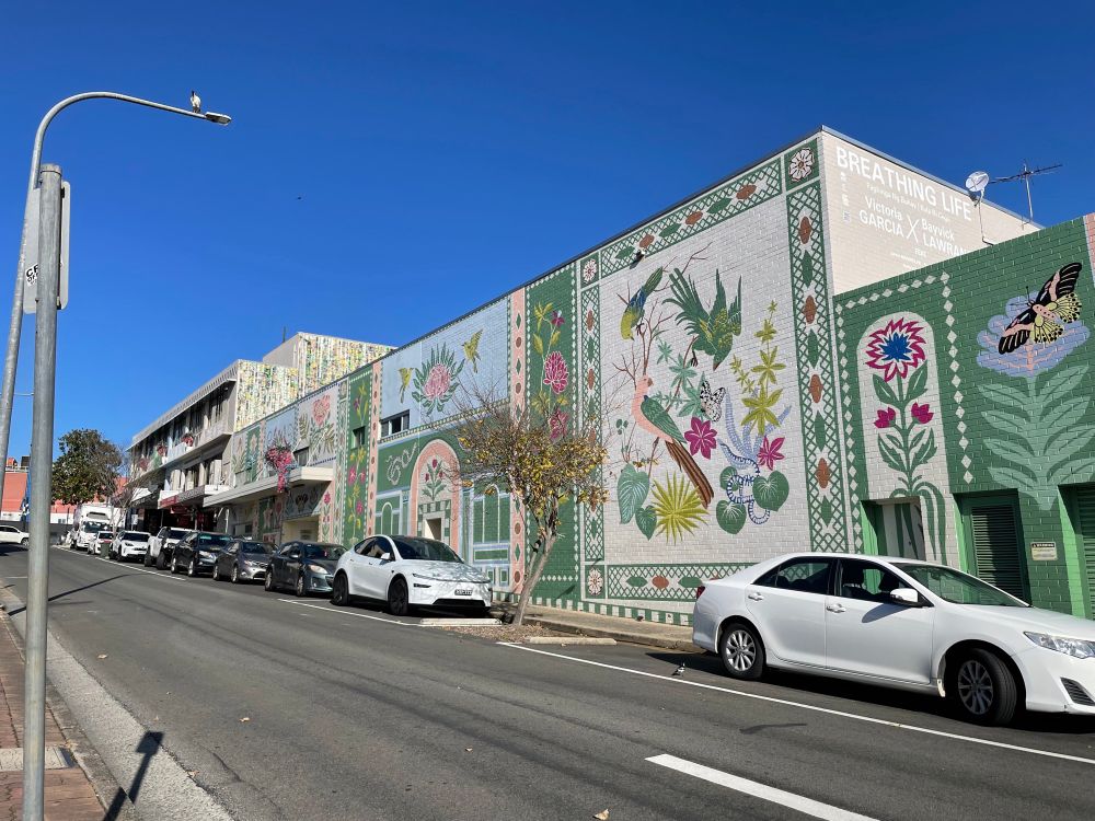 A mural of stylised birds on the brick wall of several buildings.