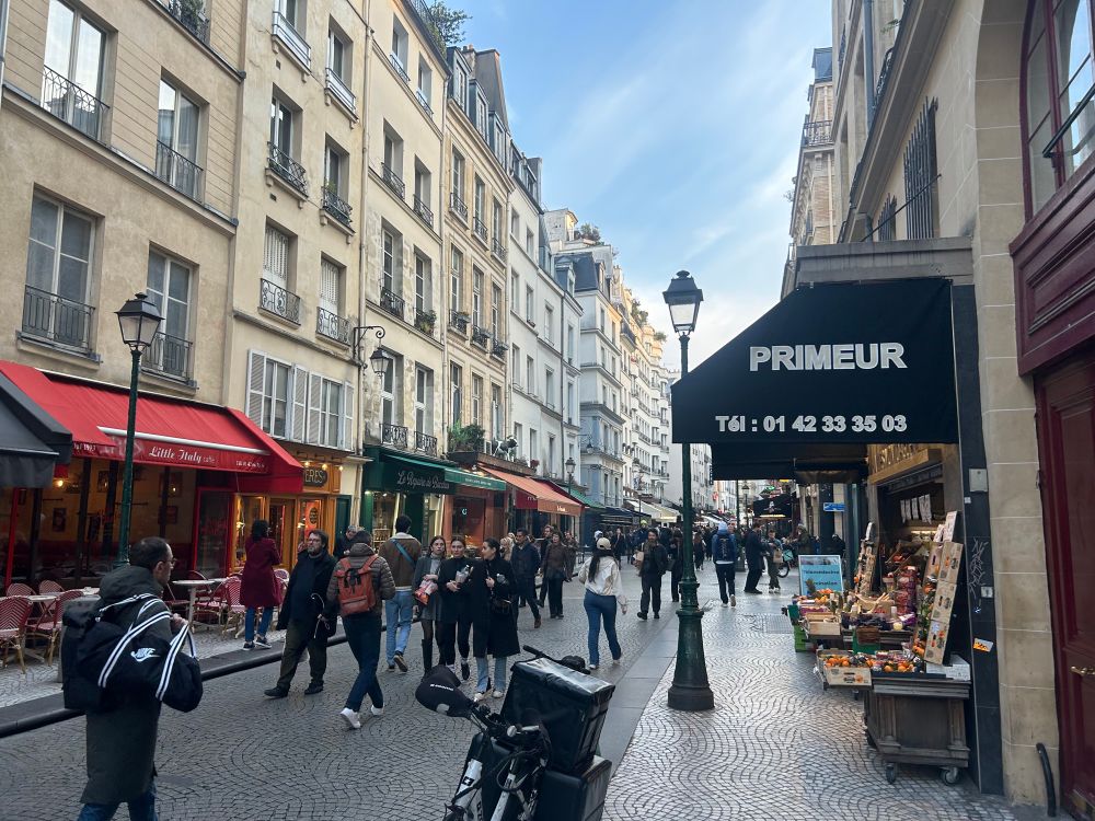 Rue de Paris en mars 2025, un vendeur de primeur en premier plan