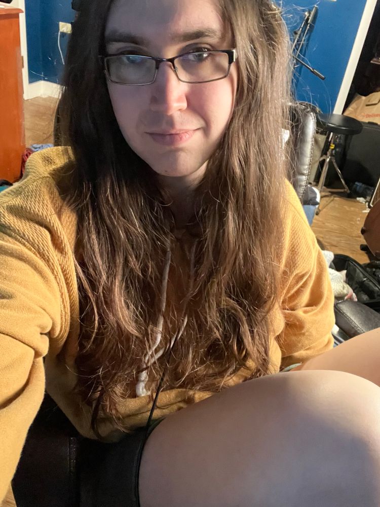 a selfie of Juliya in a yellow hoodie with her knees up.