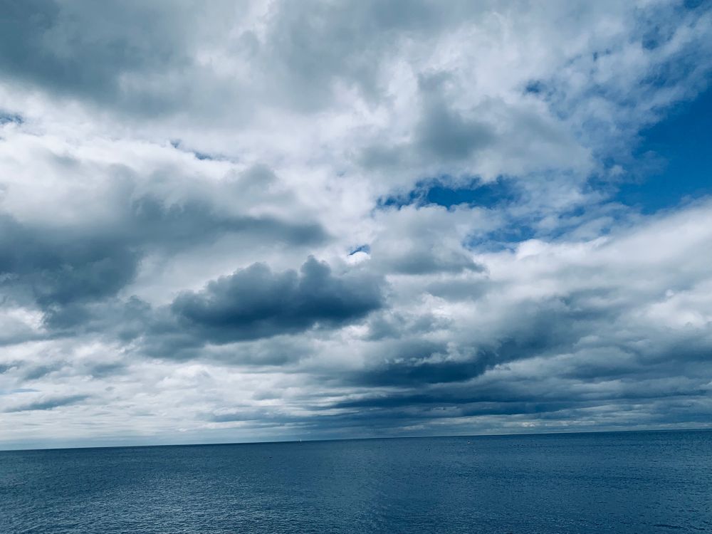 Photo of Lake Ontario with big white and black clouds looking above the water