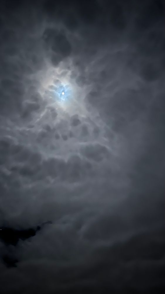 Ein Nachthimmel mit dichten, dunklen Wolken, die vom sanften Schein des Mondes erleuchtet werden und eine geheimnisvolle und ruhige Stimmung erzeugen.

A night sky with thick, dark clouds illuminated by the soft glow of the moon, creating a mysterious and serene atmosphere.