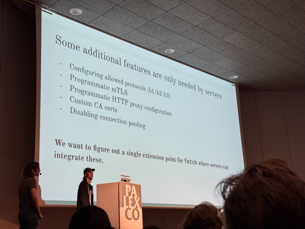 A person standing in front of a large presentation with a slide titled "Some additional features are only needed by servers"