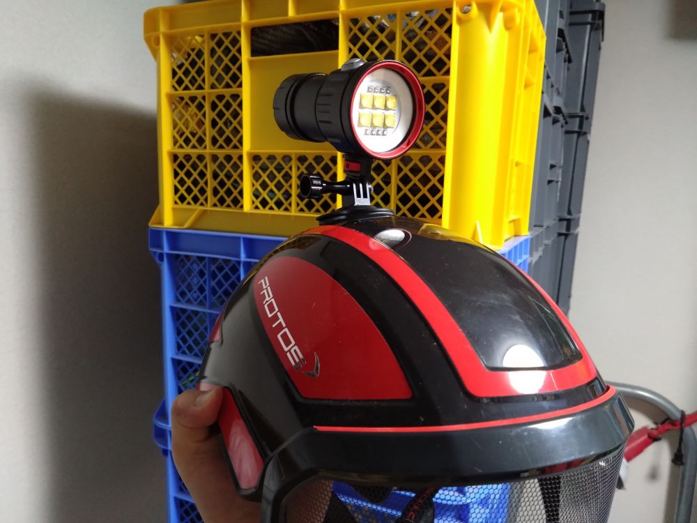 protosのヘルメットに両面テープで貼り付けられたGoProマウントを介してダイビングライトが取り付けられている