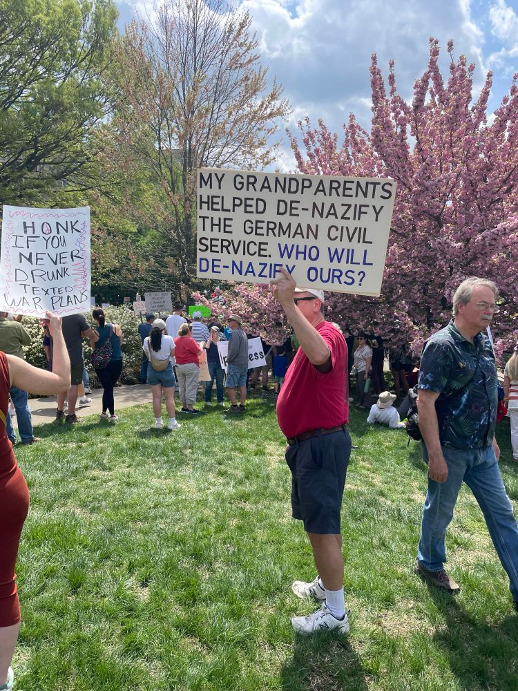 Protester with sign saying, “My grandparents helped denazify the German civil service. Who will denazify ours?”