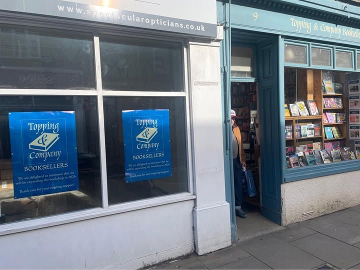 Photo of the front of Topping & Company Booksellers, next to posters advertising that they will expand into the adjacent space in 2026. 