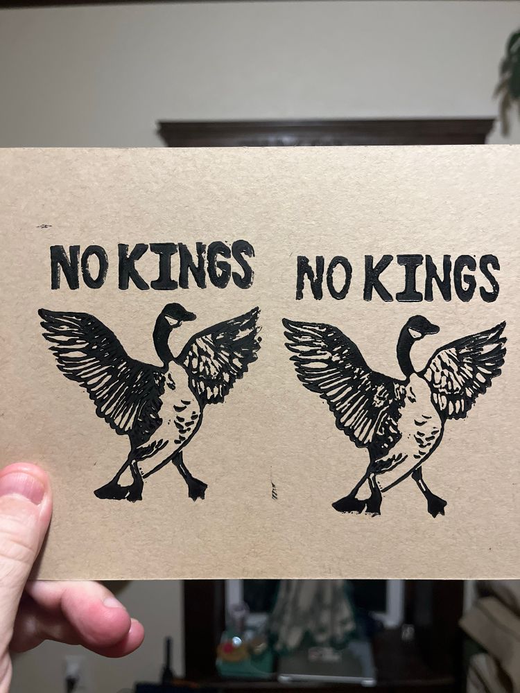 Two black linocut prints on brown paper. They show a Canada goose with wings outstretched under the words No Kings.