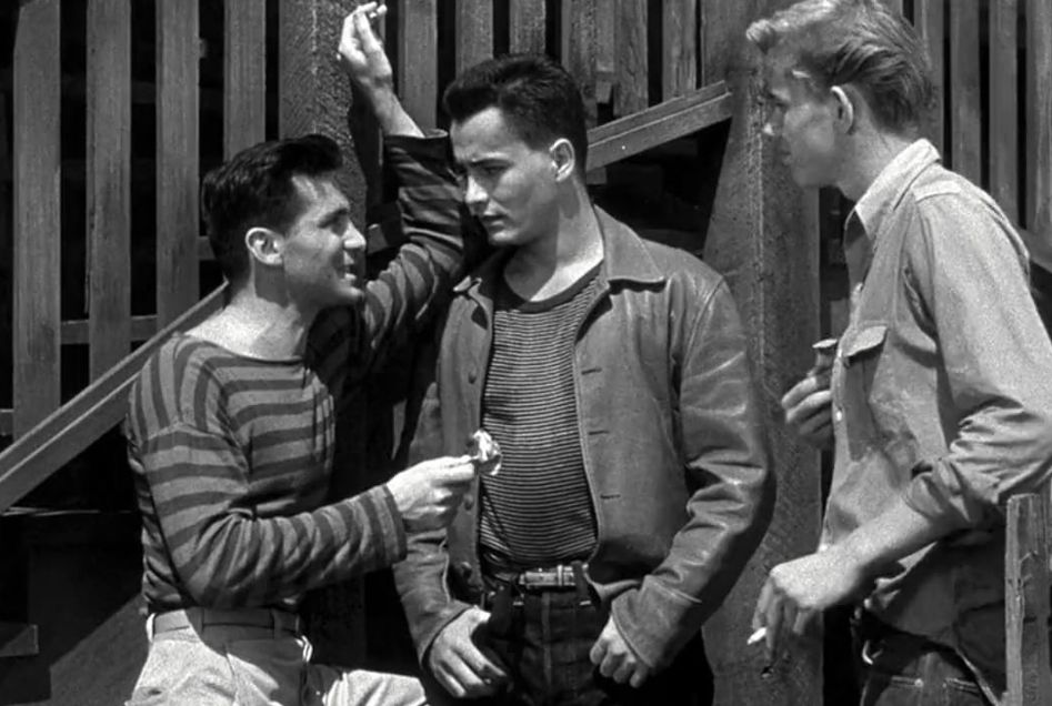 Fotograma de la película 'Llamar a cualquier puerta'. Tres jóvenes conversan, vestidos dos de ellos con camisetas de cuello redondo. El personaje de uno de ellos se llama Nicky.