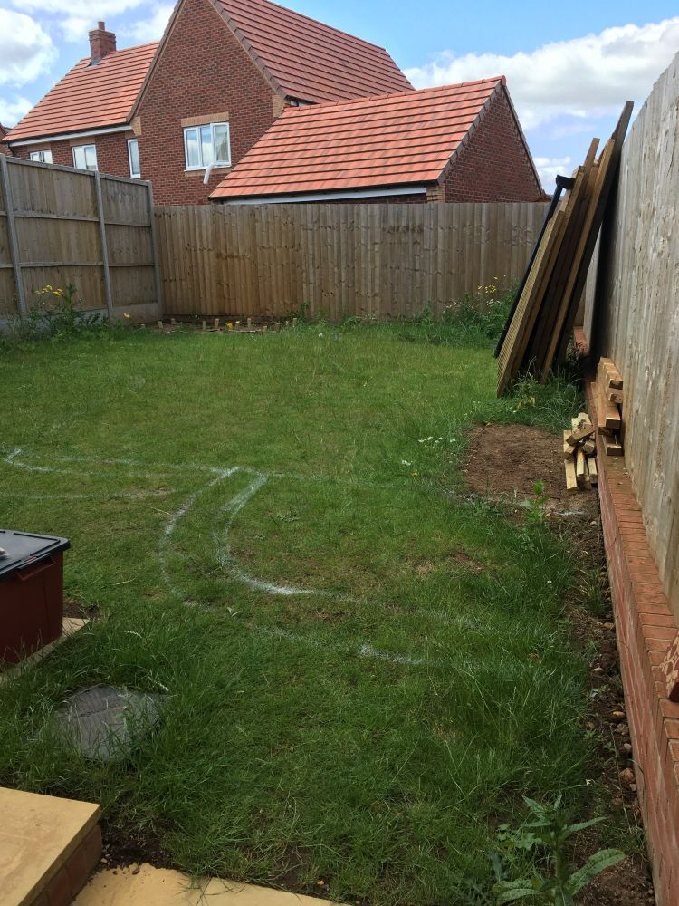Photograph of a bare new-build garden with just turf and dismantled shed. 