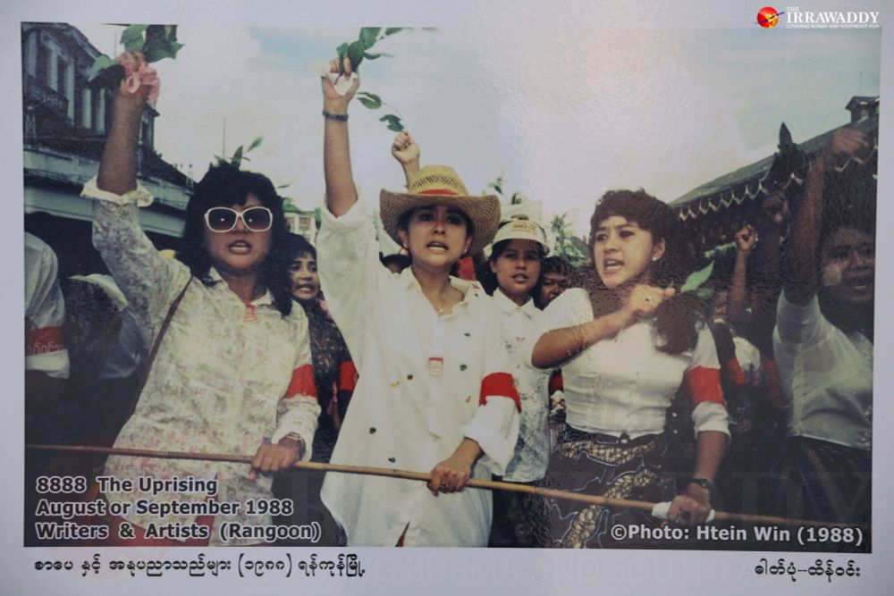 Three young Burmese women with red armbands and white shirts lead a march in Yangon. 