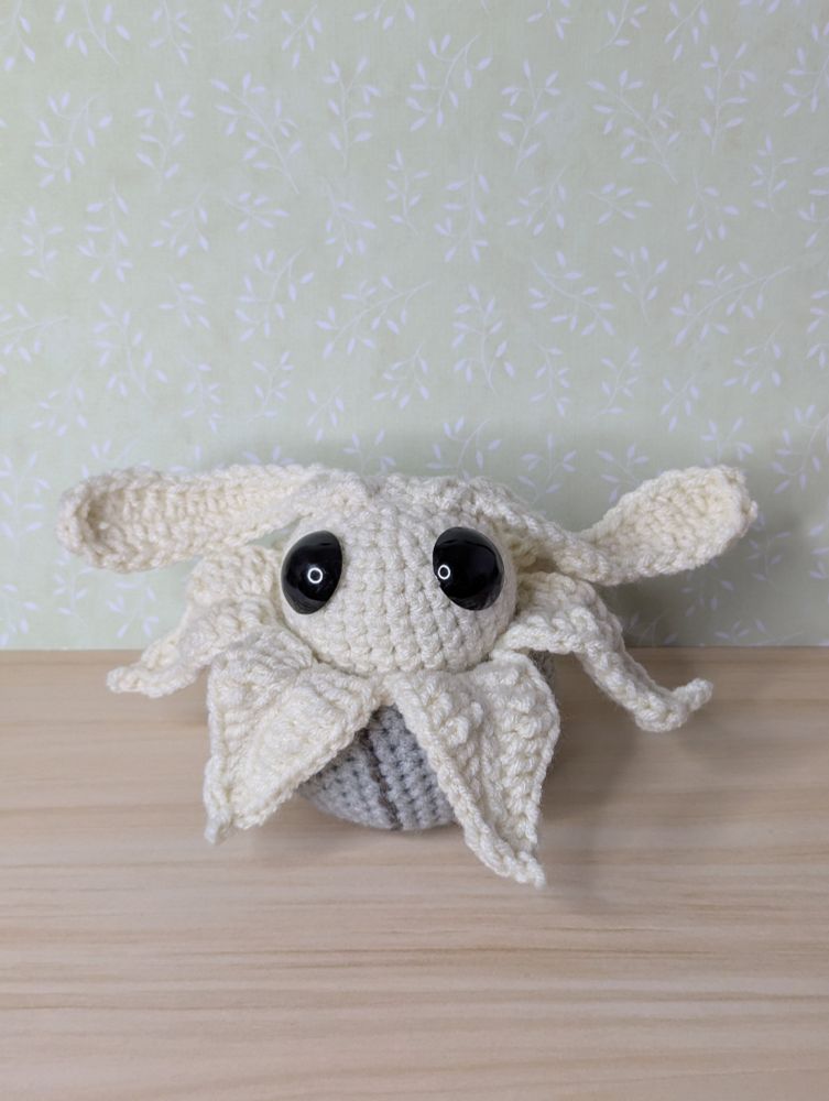 A pale crocheted bug pretending to be a plant