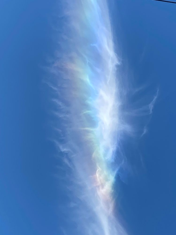 Rainbows in a wispy white cloud against a brilliant blue sky