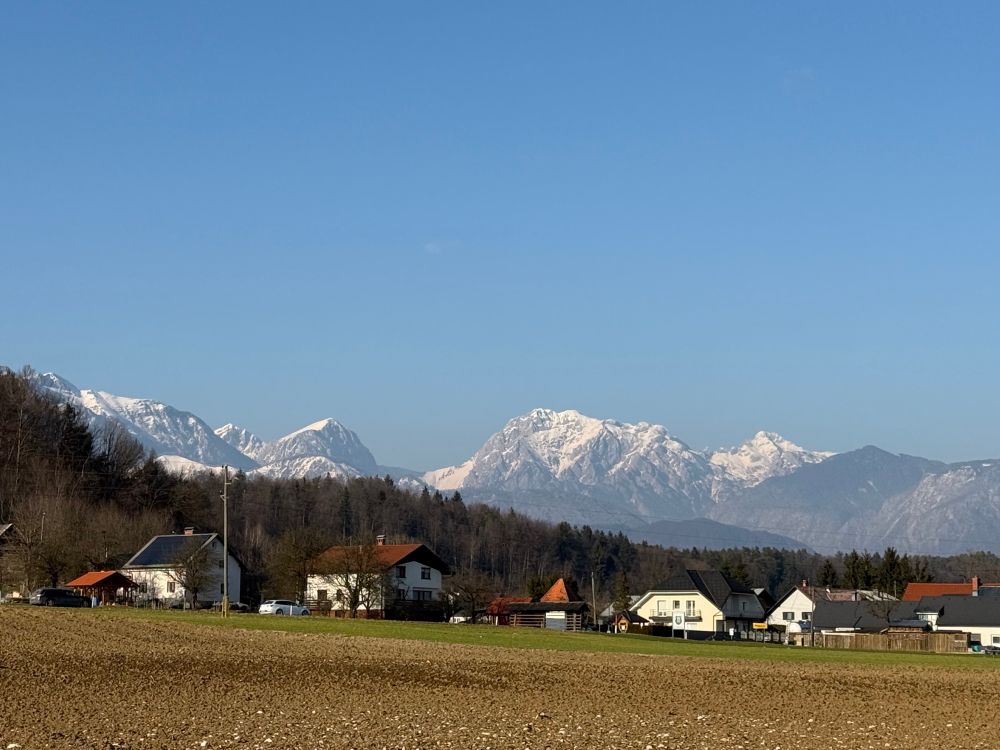 The snow dusted Julian alps peeking over a village on a sunny day in Slovenia