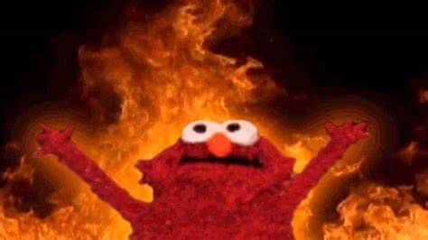 Still image of the character Elmo from the children’s program Sesame Street presiding over a world of fire.