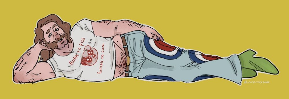 Harry du Bois laying down propped on one arm looking at the viewer. He has jeans with red white and blue circles on the side and his green snake print boots. He's also wearing a white shirt with red letters that reads " born to piss, forced to cum"
