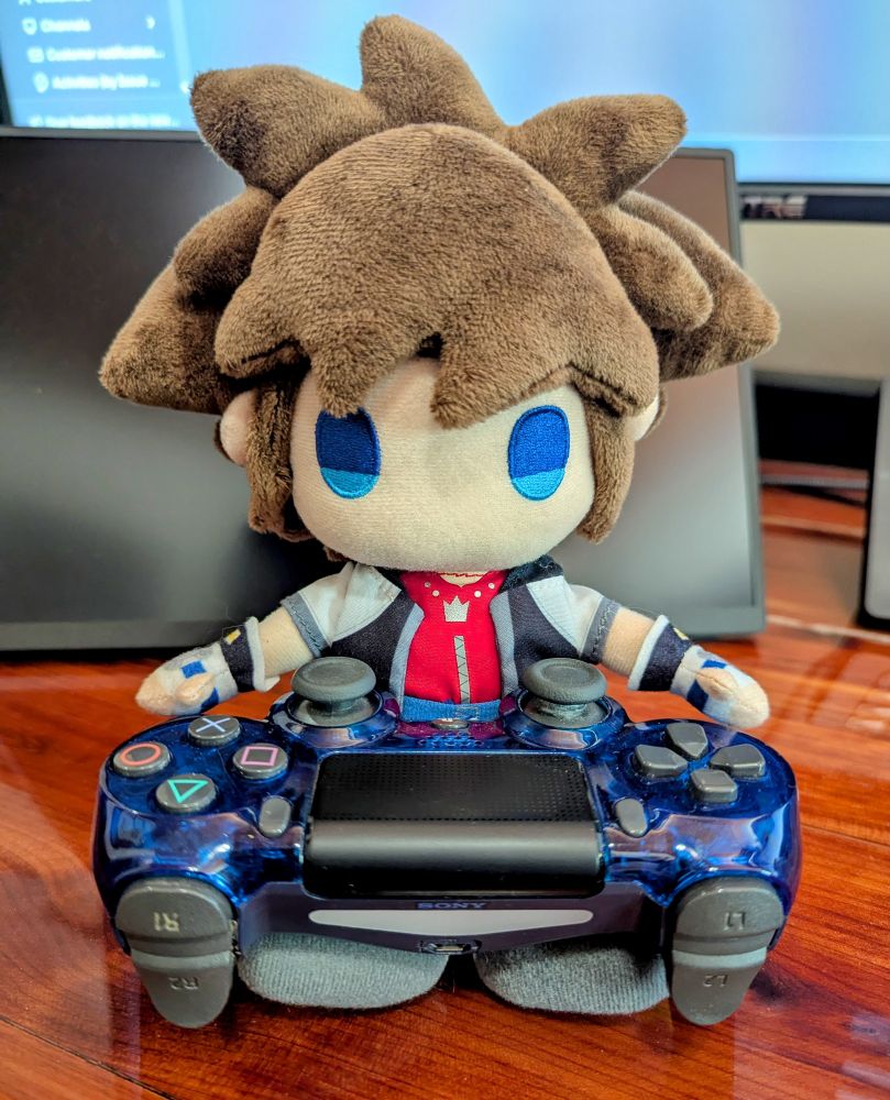 KH1 Sora plushie is holding a blue PS4 controller 