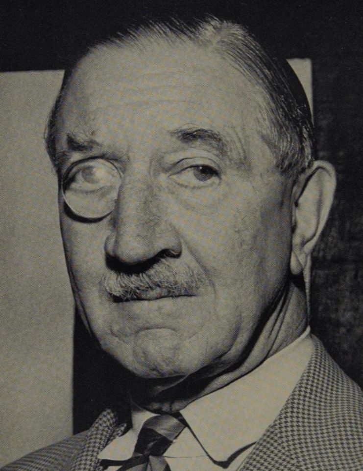 b/w photo of a man in late middle age/early old age, with a military sort of moustache and a monocle, his hair brylcreemed and very precisely parted