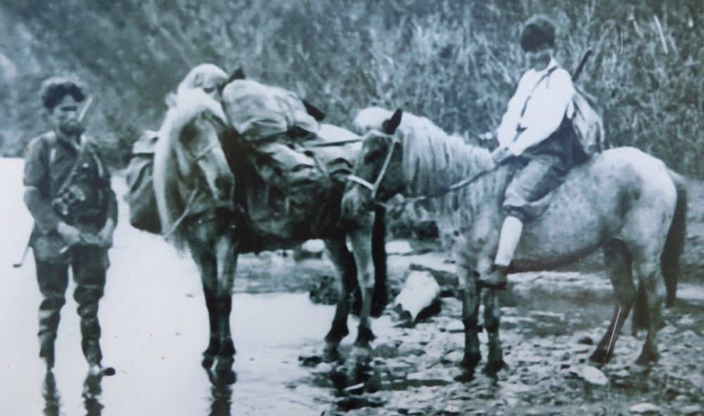 Black and white photograph of a woman on horseback and a man with a packhorse in Kamchatka.