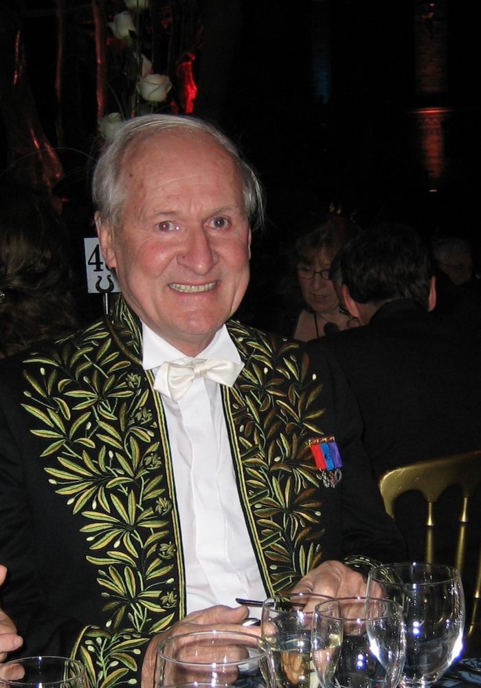 Photograph of Philippe Taquet in a fine embroidered tailcoat and white tie, wearing medals, at a formal dinner. 