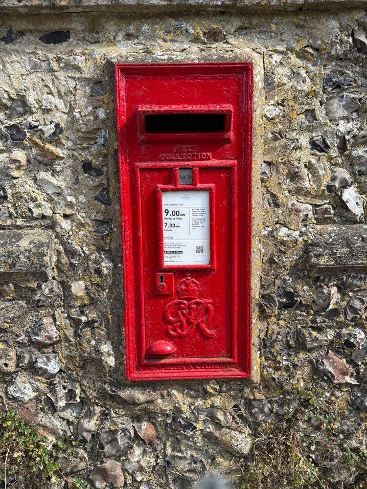 Red postbox set into a flint wall. 