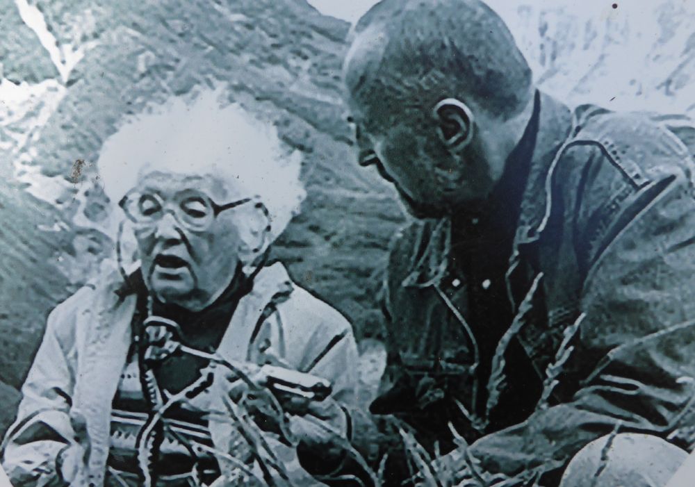Black and white photograph of an elderly Tatyana Ivanovna Ustinova being recorded describing her discovery by a man holding a microphone.