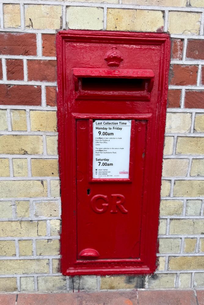 A red postbox inset into a yellow and red brick wall. 