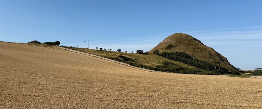 Photo of a conical hill on the right with a ridge extending to the left.