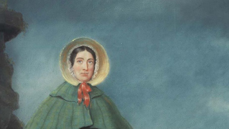 Portrait of Mary Anning in her green cloak and straw bonnet tied with a red ribbon.