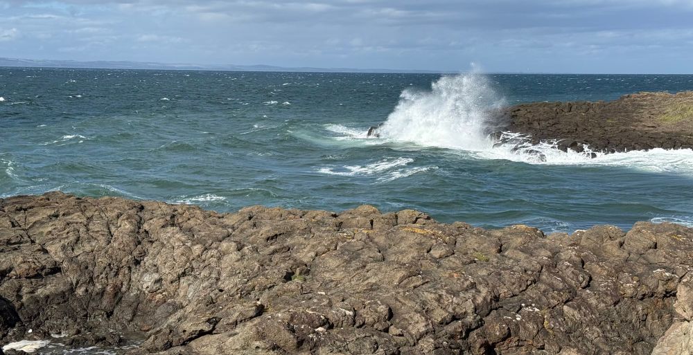Waves breaking on a rocky shore formed of a Carboniferous intrusion. 