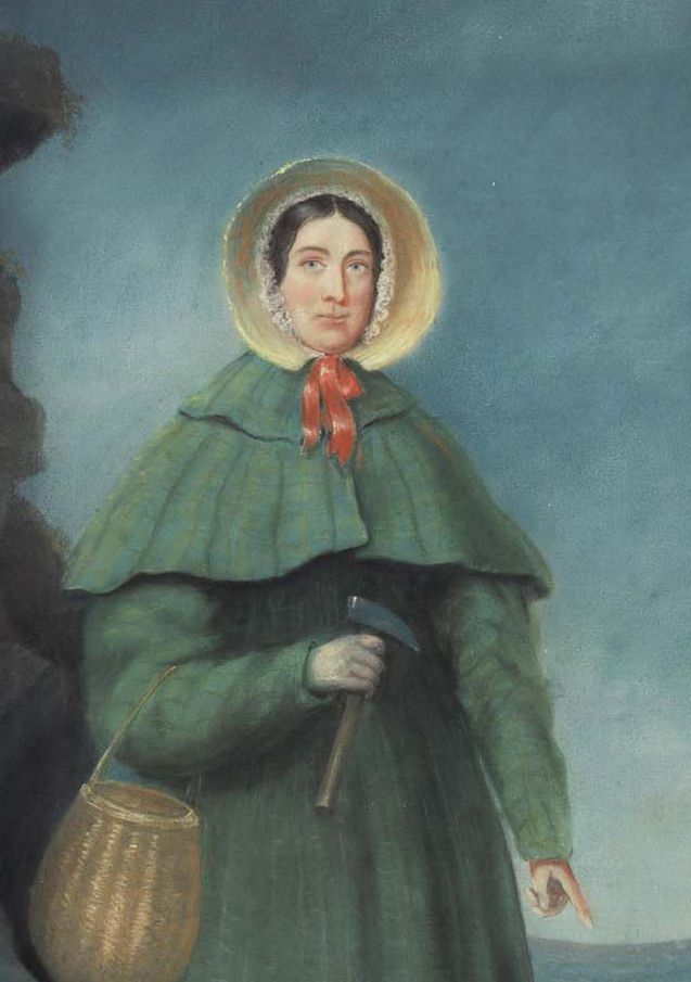 Portrait of Mary Anning wearing a green cloak and straw bonnet tied with a red ribbon. She has a basket over her right arm and holds a hammer.