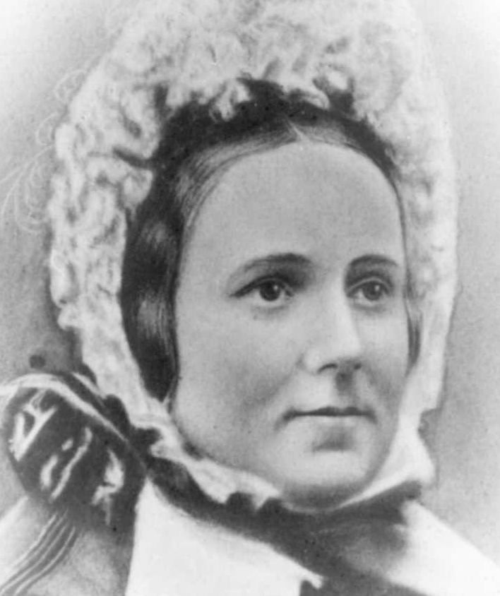 Portrait of a young woman with dark hair under a frilly bonnet.