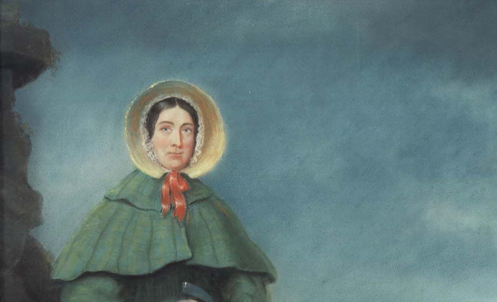 Portrait of Mary Anning wearing a green cloak and straw bonnet tied with a red ribbon.
