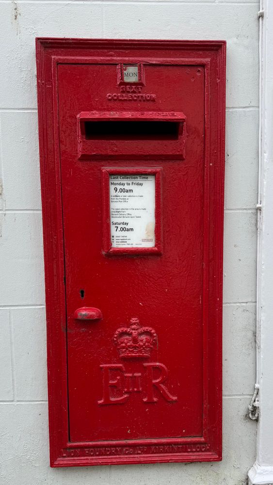 Red post box set into a white wall. 