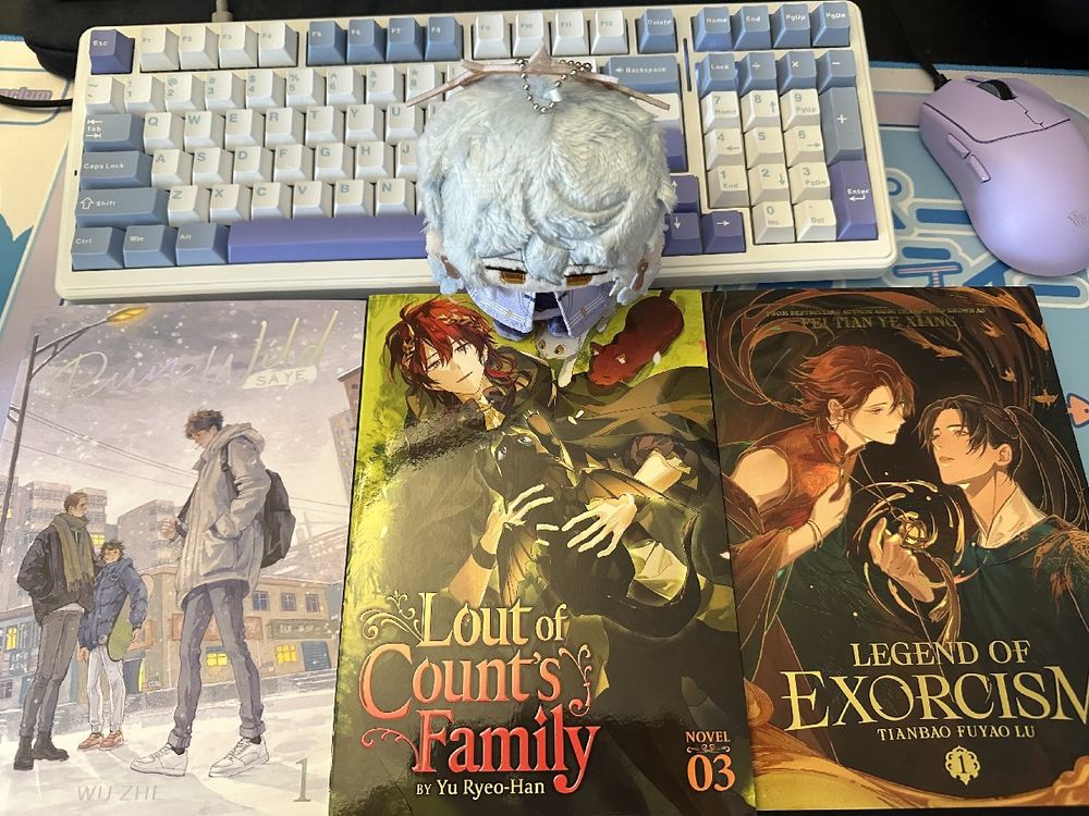 A small Sunday plushie sitting on top of one of three novels. The three novels are : Run Wild Vol. 1, Lout of Count's Family Vol. 3 and Legend of Exorcism Vol 1.