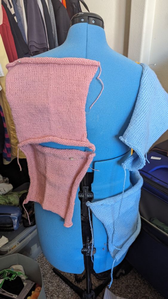 Back of a dress form with several knit panels pinned to it