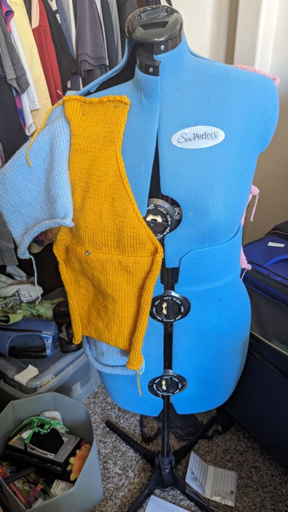 Front of a dress form with several knit panels pinned to it 