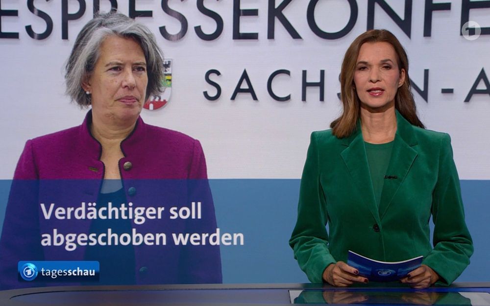 Das Bild zeigt zwei Frauen, die offensichtlich an einer Pressekonferenz teilnehmen. Links steht eine Frau mit graumeliertem Haar und einem pinkfarbenen Blazer. Rechts steht eine Frau mit braunen Haaren und einem grünen Blazer. Vor ihnen befindet sich ein Tisch, und im unteren Teil des Bildes ist der Text "Verdächtiger soll abgeschoben werden" zusammen mit dem Tagesschau-Logo zu sehen.