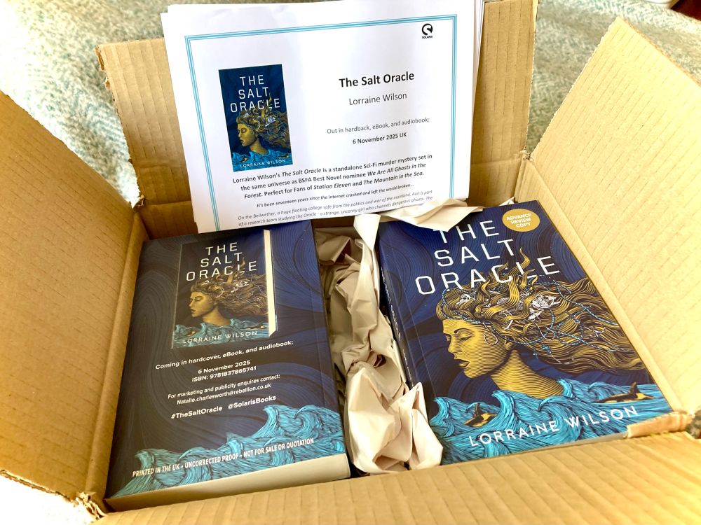 photo of a box full of delicious THE SALT ORACLE advance review copies, plus information sheet. The cover is too gorgeous for words, but umm... in a kind of woodcut art style - light blue waves with gold orcas against a dark blue background, and dominating it all, the profile of a gold girl, eyes closed, her tangled hair full of fish and bird skeletons, and fishing line with sliver hooks. 