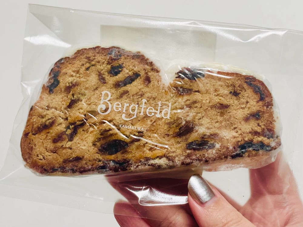 個包装されたシュトレンのスライスを手に持っている写真。シュトレンは「ベルグフェルド」というベーカリーのもの。