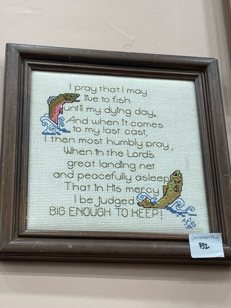 A cross stitch with two fish framing a prayer that reads: “I pray that I may live to fish until my dying day. And when it comes to my last cast, I then most humbly pray, When in the Lord’s great landing net and peacefully asleep. That in His mercy I be judged BIG ENOUGH TO KEEP!” It is priced at $32. 