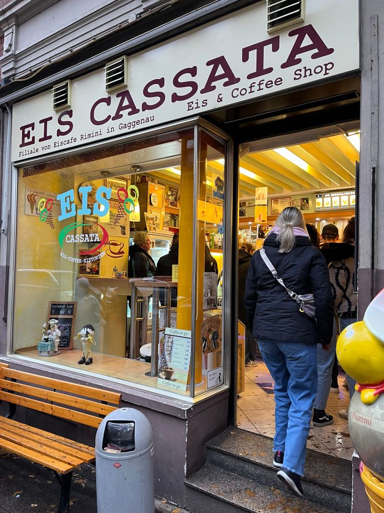 Frontscheibe der Eisdiele Eis Cassata. Im Innern brennt Licht und es sind dort viele Menschen.