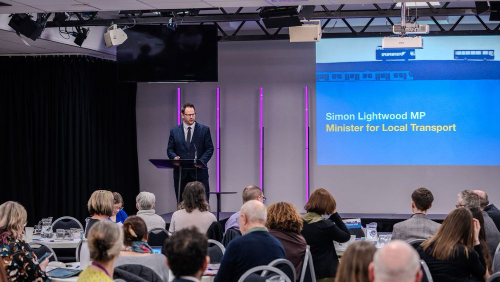 Simon Lightwood on stage speaking at the INTS roadshow. Audience in foreground  of the photo