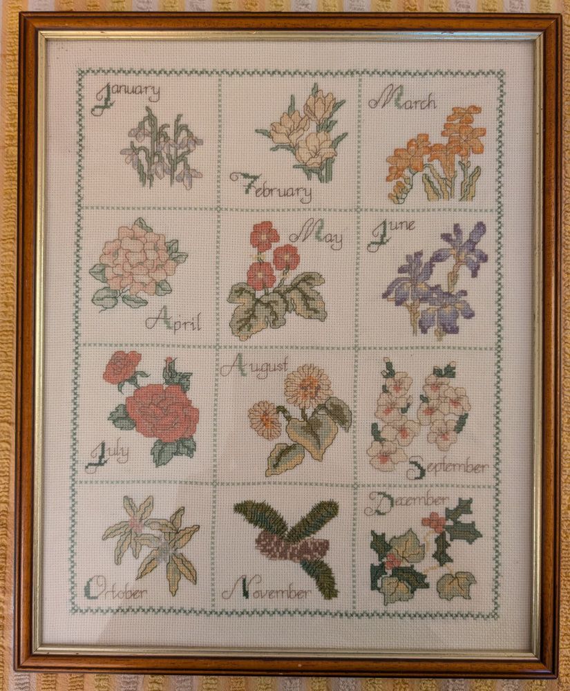 Framed needlework depicting flora for each month.