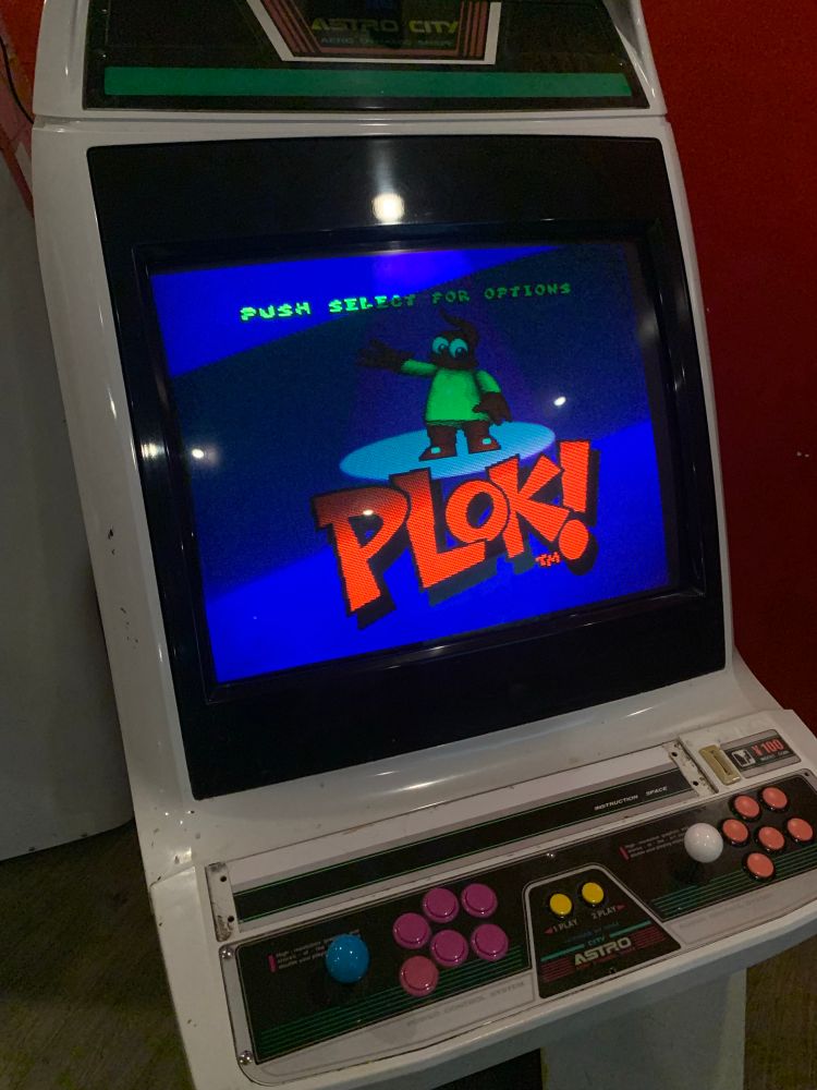 astro city arcade cabinet with the plok! title screen on the display