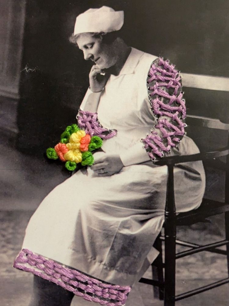 A historical photo of a person in a traditional nurse uniform with decorative, colorful crochet details on the sleeves and holding crochet flowers, sitting on a wooden stool and appearing thoughtful.